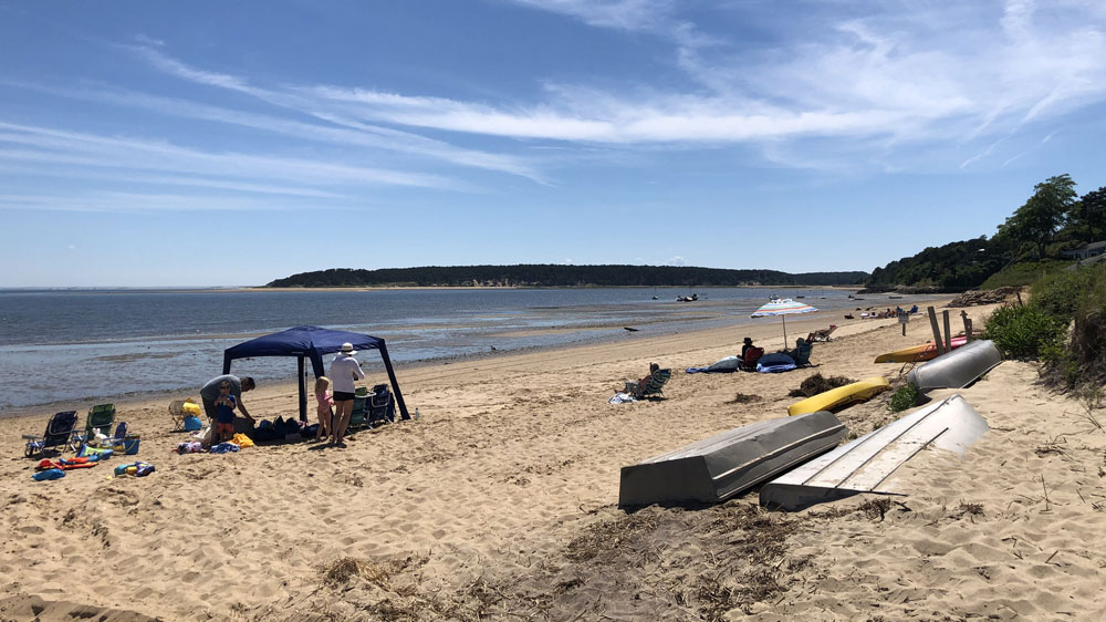 Boats and beachgoers line the shore of Powers Landing in Wellfleet, Cape Cod.