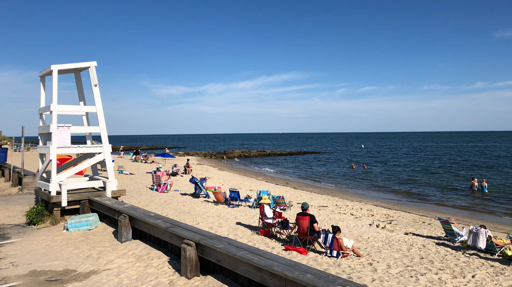 Crowds sit under the lifeguard tower at Glendon Road Beach in Dennis, Cape Cod.