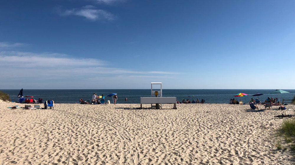 Beachgoers spread out to the sides of the lifeguard tower at South Village Beach in Dennis, Cape Cod.
