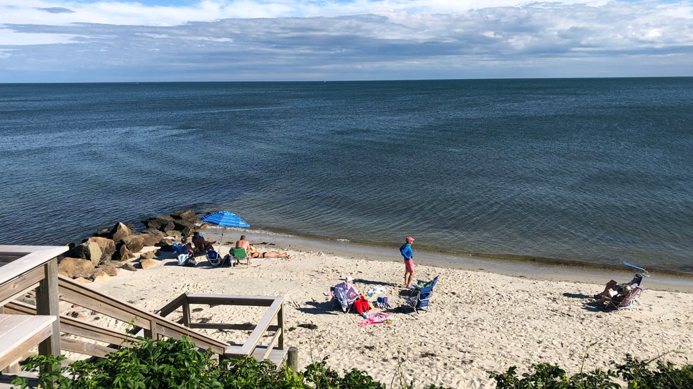 People relax at the bottom of the stairs at the Wah-Wah-Taysee Road beach in Harwich, Cape Cod.