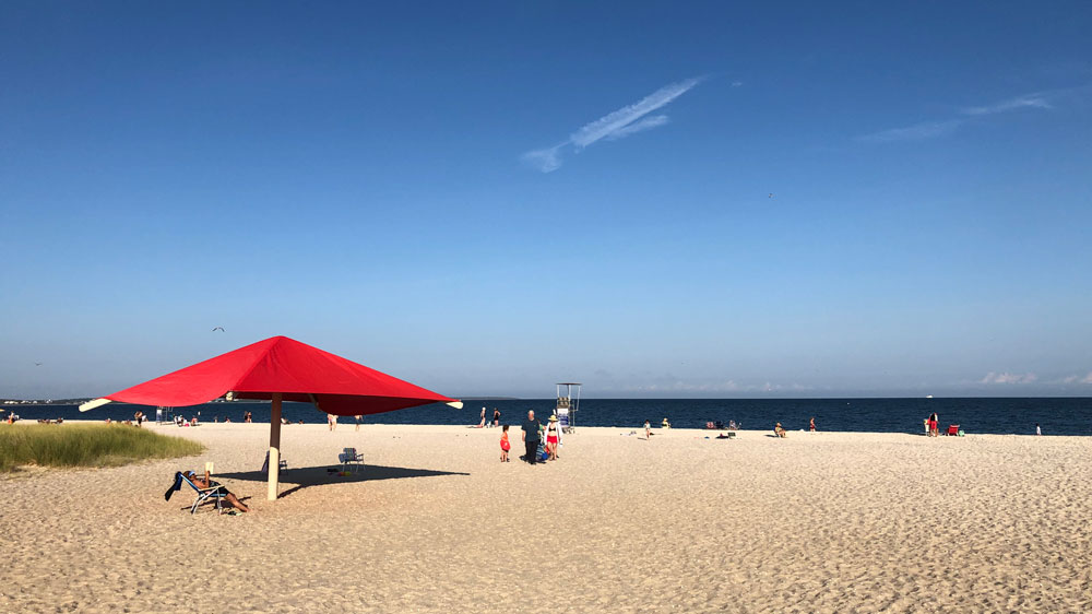 A woman reads a book under a giant umbrella at Dowse's Beach in Barnstable, Cape Cod.