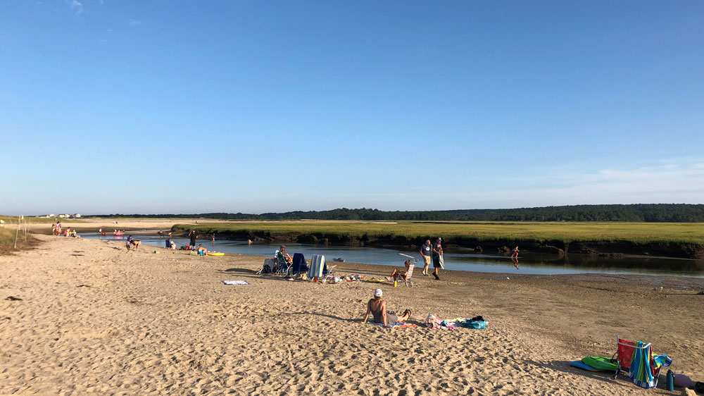 Families relax on the beach at Sandwich Boardwalk in Sandwich, Cape Cod.