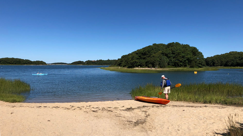 A kayaker pulls his boat on shore at Monks Park in Bourne, Cape Cod.