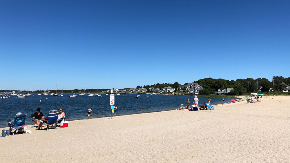 Beachgoers relax on the shores of Monument Beach in Bourne, Cape Cod.