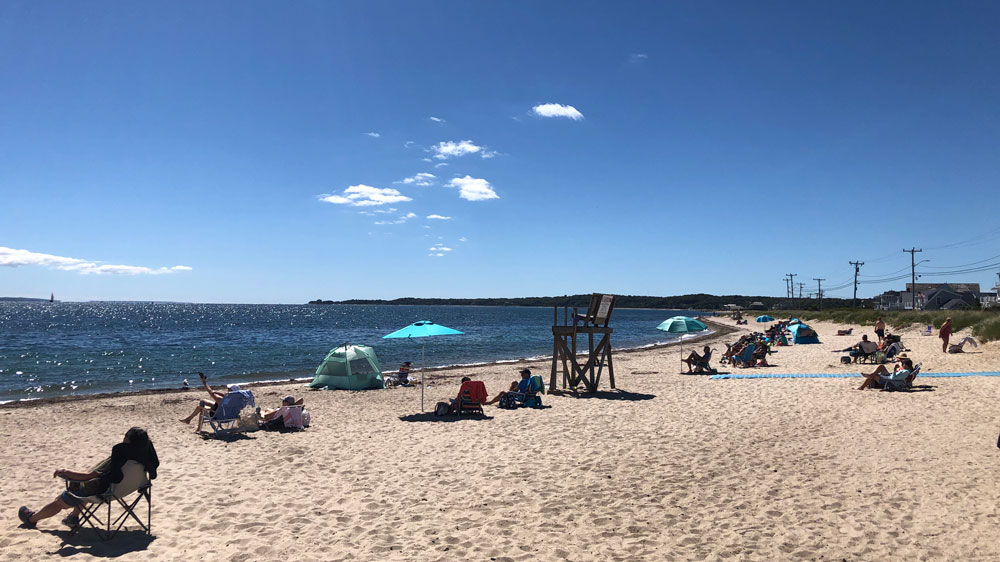 A vacant lifeguard chair sits among the crowd at Surf Drive Beach in Falmouth, Cape Cod.